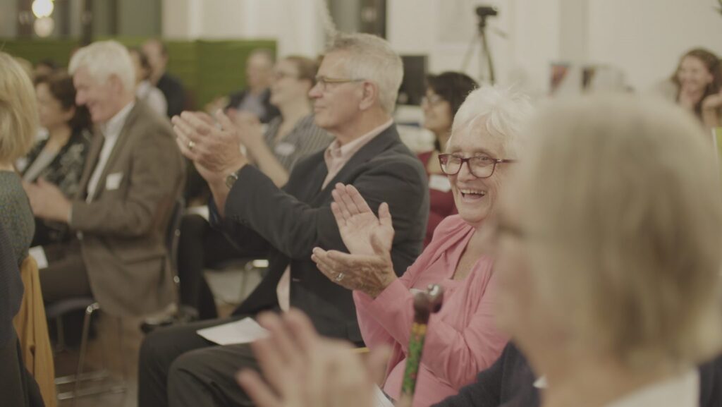 Crowd clapping happily at a RDS seminar.