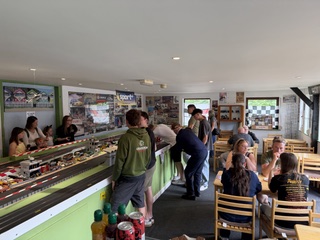 People looking at the scaletrix and sitting on tables and chairs at the toy car museum.